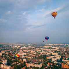 色彩斑斓的热空气气球飞行小欧洲城市夏天日落