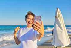 快乐中年女人会说话的智能手机视频调用海滩