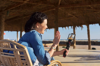 中间岁的女人智能手机网络摄像头会说话的记录视频桑迪海滩