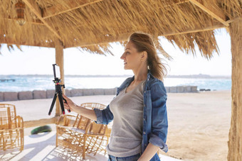 中间岁的女人智能手机网络摄像头会说话的记录视频桑迪海滩