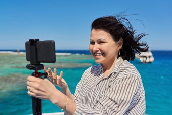 快乐女人记录视频流智能手机背景的地方潜水浮潜