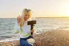 女少年智能手机三脚架海日落海滩记录视频