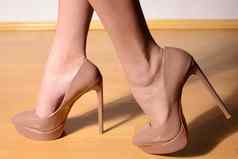 女脚浅褐色的穿高跟鞋的鞋子木地板上
