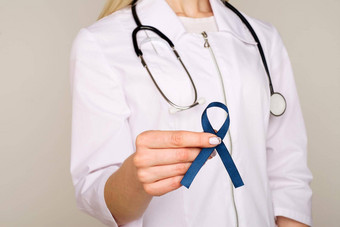 医生手持有蓝色的丝带糖尿病结直肠癌症意识