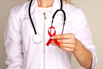 女医生援助艾滋病毒红色的丝带癌症概念医生持有红色的丝带意识世界艾滋病一天12月