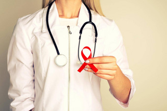 女医生援助艾滋病毒红色的丝带<strong>癌症</strong>概念医生持有红色的丝带意识<strong>世界</strong>艾滋病一天12月