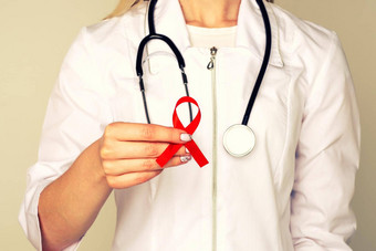 女医生援助艾滋病毒红色的丝带<strong>癌症</strong>概念医生持有红色的丝带意识<strong>世界</strong>艾滋病一天12月