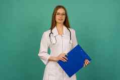 美丽的年轻的女孩护士实习医生蓝色的文件夹微动气压计蓝色的背景