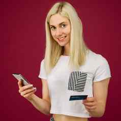 年轻的微笑女人购买在线持有智能手机信贷卡手