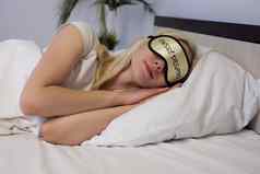 年轻的美丽的女人睡觉床上眼睛面具