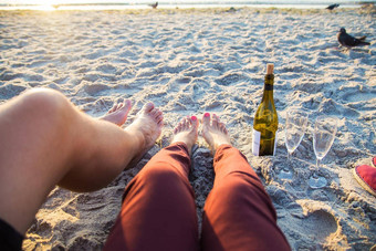 快乐时尚的一对腿海滩日光浴喝酒