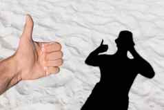 男人的手显示很酷的手指背景黑色的轮廓影子白色海滩沙子