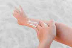 手年轻的女孩涂片防晒霜太阳保护手背景海滩特写镜头
