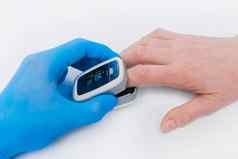 医生的手乳胶医疗手套持有设备测量氧气血pulsexymeter手指上了年纪的女人白色背景