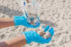 男人的手保护医疗手套持有袋垃圾桩贝壳特写镜头概念清洁海海滩浪费处理打击污染环境