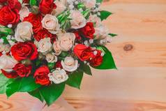 婚礼花束白色红色的玫瑰绿色叶子木地板上背景