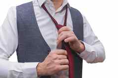男人的手培养白色衬衫灰色背心系红色的领带特写镜头