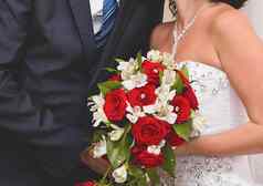 新娘新郎白色婚礼衣服持有花束美丽的花白色红色的玫瑰特写镜头