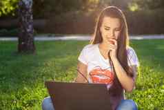 年轻的女人电脑绿色草公园教育学习自由工作户外放松概念的想法背景太阳耀斑