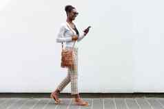 一边肖像年轻的非洲美国女人走白色墙手机
