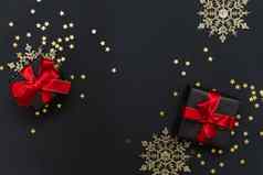 一年的礼物红色的弓黑色的背景五彩纸屑黄金雪花球准备时尚的圣诞节聚会，派对