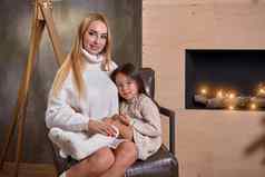 美丽的妈妈。女人白色毛衣拥抱女儿快乐的好玩的情绪爱内部家庭