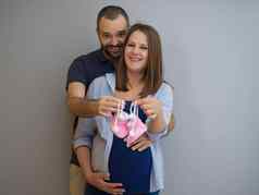 怀孕了夫妇持有新生儿婴儿鞋子