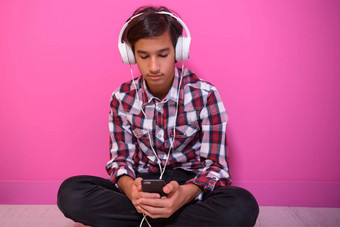 阿拉伯语十几岁的男孩穿耳机听音乐粉红色的背景