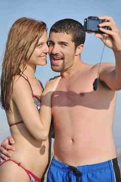 快乐年轻的夫妇爱采取照片海滩