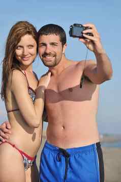 快乐年轻的夫妇爱采取照片海滩