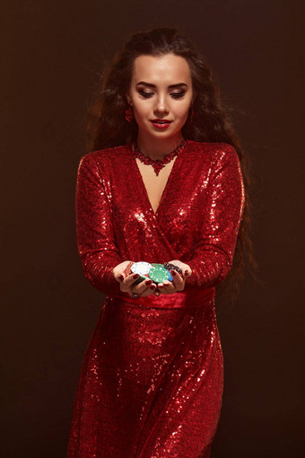 年轻的漂亮的幸运的浅黑肤色的女人女人红色的晚上衣服持有扑克芯片手显示奖金