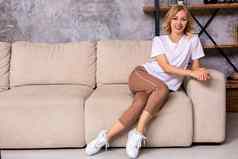 年轻的女人坐着沙发上放松首页休闲风格室内拍摄