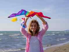 年轻的女人持有风筝海滩秋天一天
