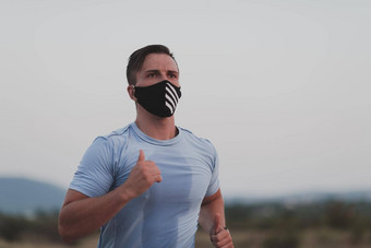 健身男人。湿运动衣服穿黑色的保护脸面具运行在户外城市冠状病毒爆发科维德物理慢跑活动体育运动健身正常的