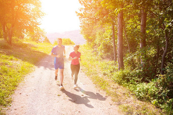 年轻的夫妇慢跑阳光明媚的一天自然