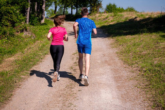 年轻的夫妇慢跑阳光明媚的一天自然
