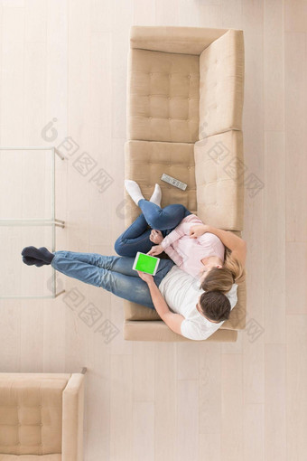 年轻的夫妇生活房间平板电脑前视图