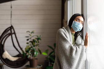伤心亚洲女孩医疗脸面具窗口向往走生病了捕捉科维德流感