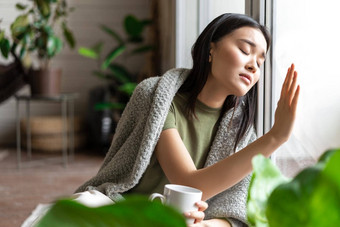 伤心心碎的亚洲女人触碰玻璃窗口感觉生病的向往住首页生病了