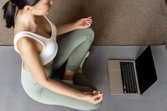 裁剪拍摄亚洲女人冥想地板上席<strong>首页</strong>听冥想播客移动PC实践瑜伽在线courase穿<strong>运动服</strong>