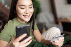 年轻的亚洲女人购买在线商店移动电话信贷卡购物首页