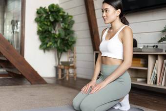 年轻的亚洲女人锻炼首页冥想瑜伽练习生活房间穿体育穿集中