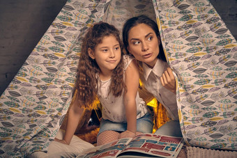 妈妈。女儿坐着超视距雷达帐篷枕头阅读故事快乐家庭
