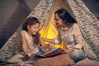 妈妈。女儿坐着超视距雷达帐篷枕头阅<strong>读故事</strong>快乐家庭