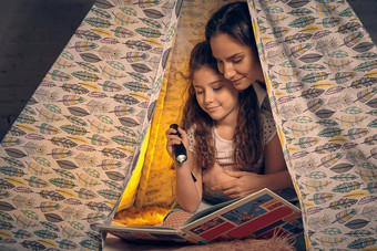 妈妈。女儿坐着超视距雷达帐篷阅<strong>读故事</strong>手电筒快乐家庭