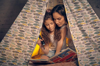 妈妈。女儿坐着超视距雷达帐篷阅读故事手电筒快乐家庭