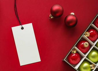 圣诞节出售假期时尚设计概念空白服装标签圣诞节装饰饰品红色的纸背景平铺模型