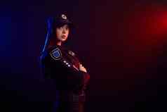 女警察官摆姿势相机黑色的背景红色的蓝色的背光