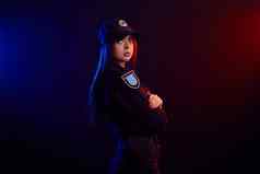 女警察官摆姿势相机黑色的背景红色的蓝色的背光