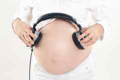 深思熟虑的怀孕了女人未出生的孩子听音乐耳机